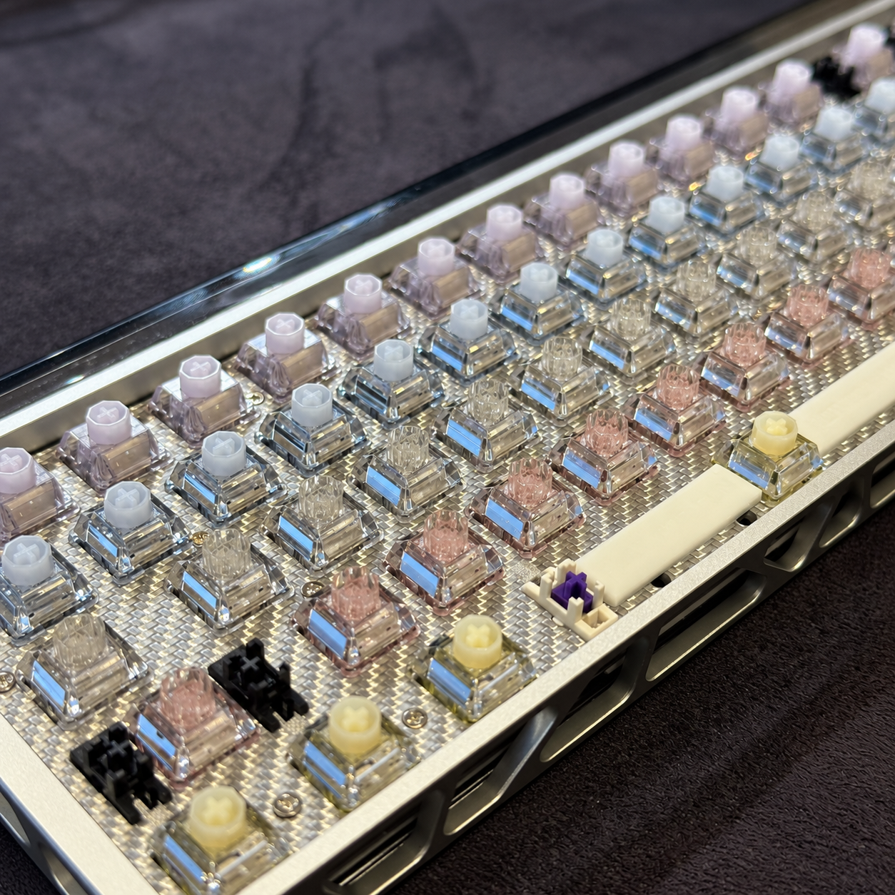 Close-up of a silver keyboard with clear switches and mixed pastel keycaps